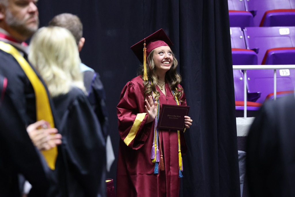 A Viewmont High graduate happily looks up while holding their diploma cover. 