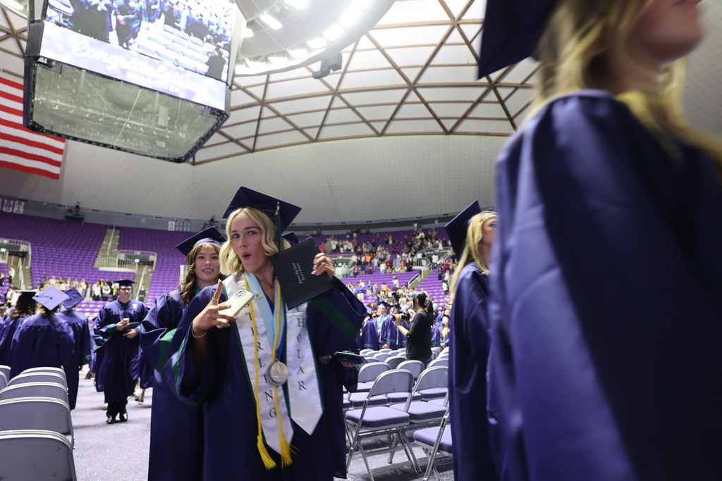 A Syracuse High graduate holds up her diploma and looks shocked as she exits the Dee Events Center.