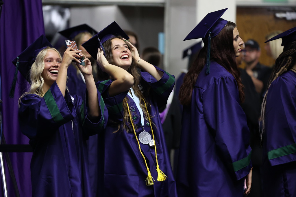 A Syracuse High graduates smiling and looking up at the jumbotron.