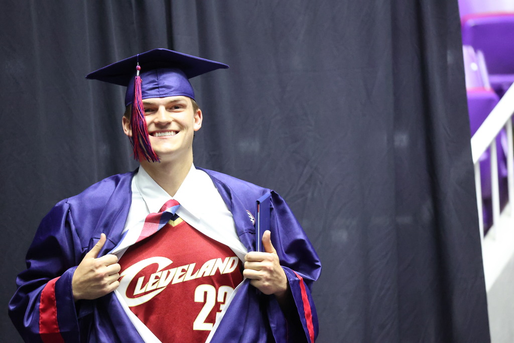 A Woods Cross graduate opens his shirt super-man style to reveal a Cleveland jersey.