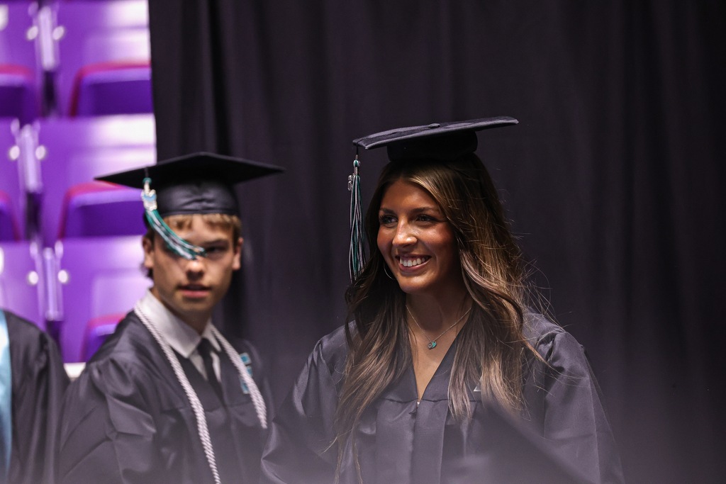 Farmington High graduate smiles as they walk across the stage.