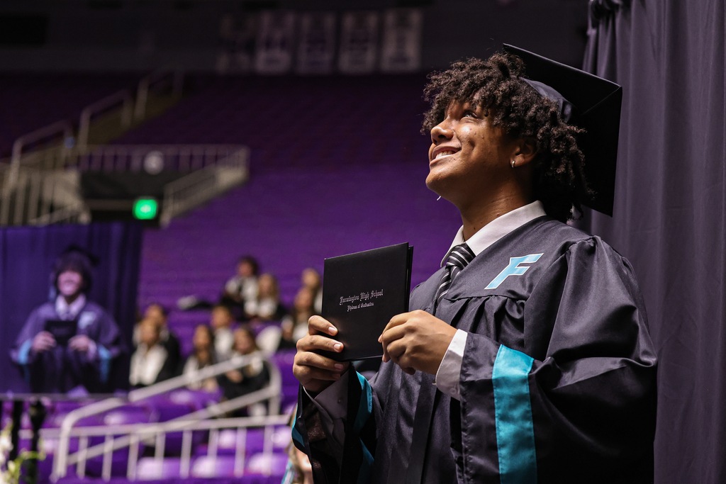 Farmington High graduate smiles while holding his diploma cover. 