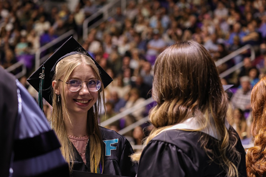 Farmington High graduate shakes the hand of Board Member Joani Stevens.