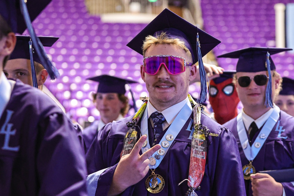 A Layton High graduate wearing hot pink sunglasses smiles at the camera.