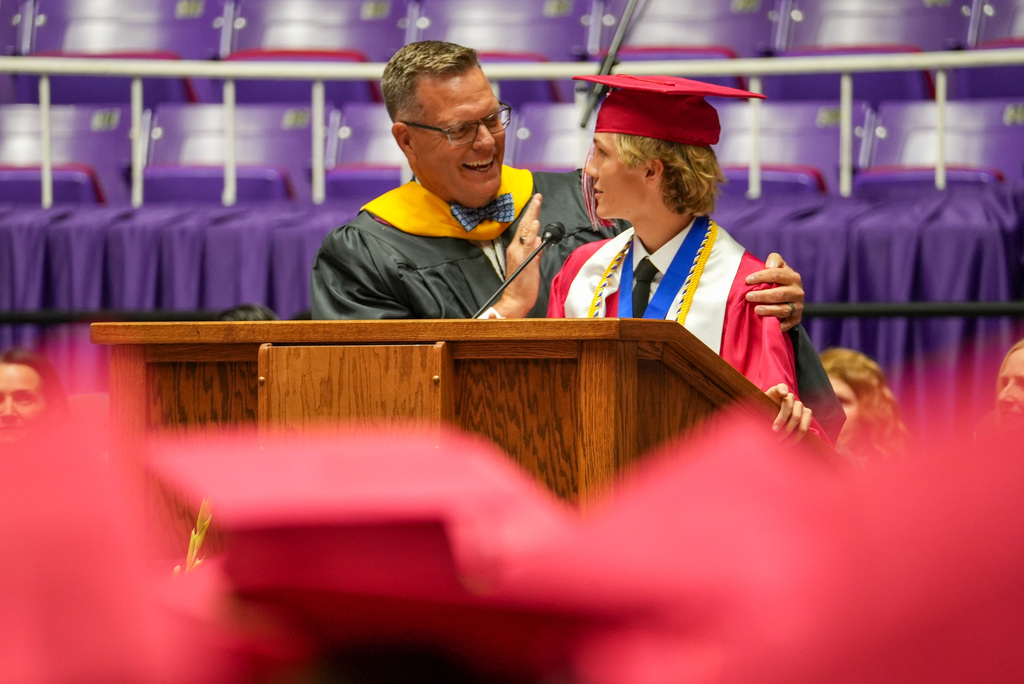 Bountiful High graduate talks with principal Travis Warnick at the podium. 