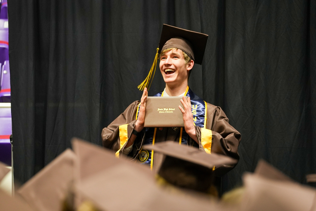 Davis High graduate smiling with their diploma cover.
