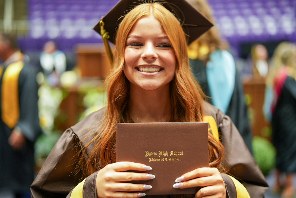 Davis High graduate smiling with their diploma cover.