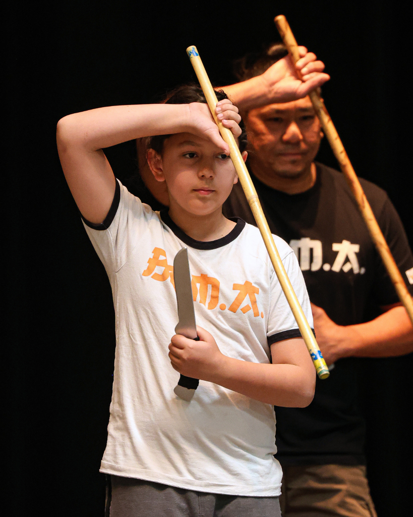 A student and an adult hold bamboo sticks and knives to show off at Foxboro's AAPI Assembly.