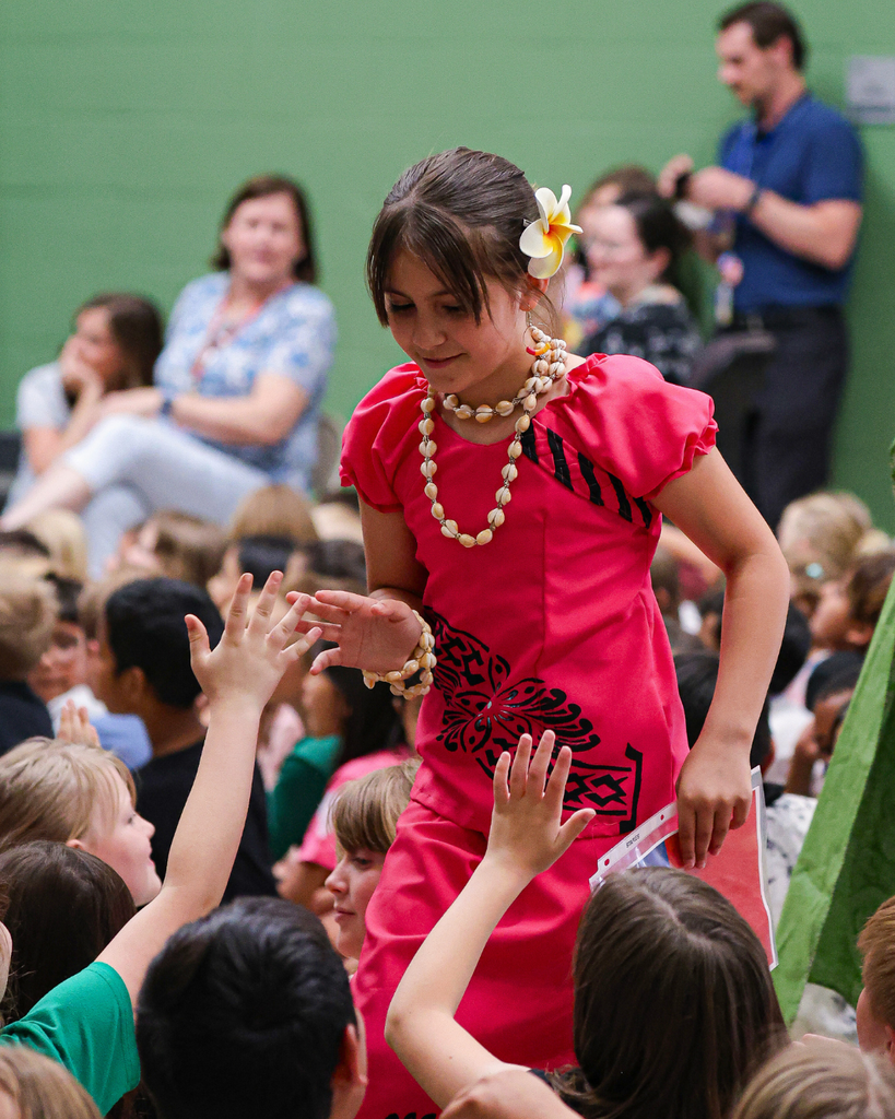 A student receives high fives from her classmates as she walks to her seat.