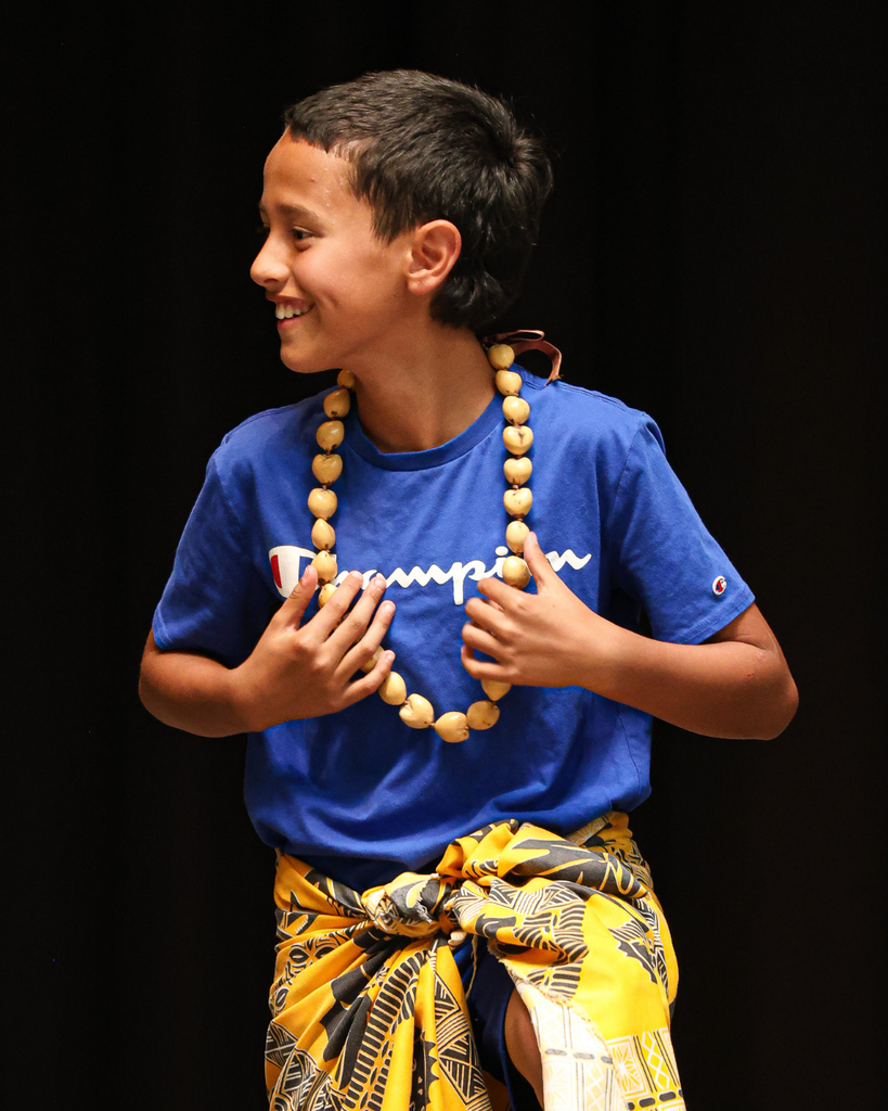 A student wearing native clothing smiles.