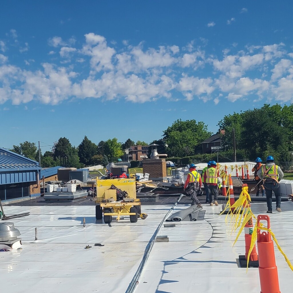 construction workers installing new roofing membrane over existing roof