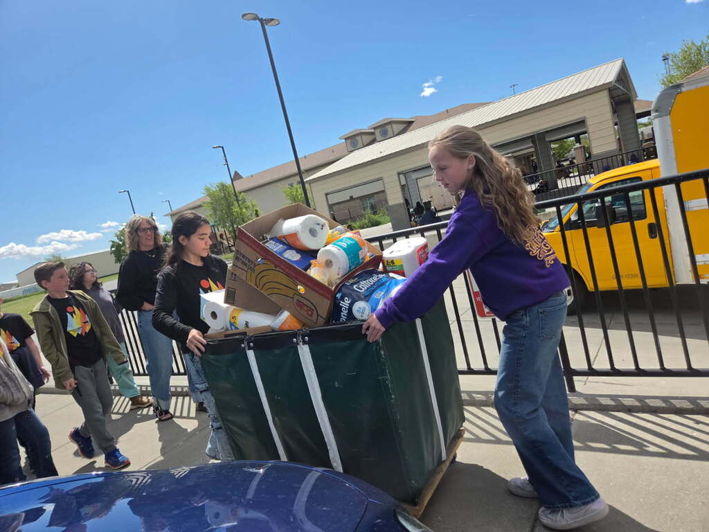 Students pushing a cart full of paper supplies.