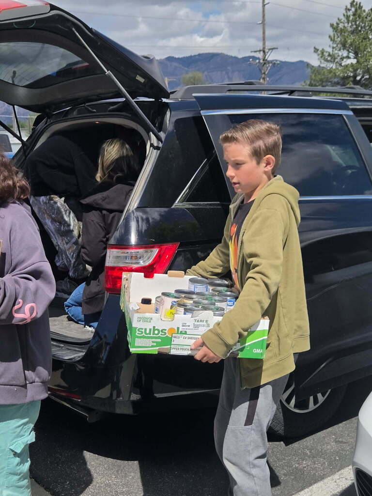 A student carrying a box of cans.