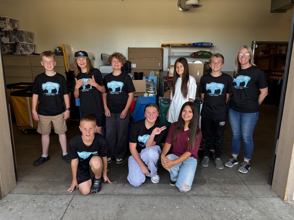 A group of students wearing black shirts smile at the camera.