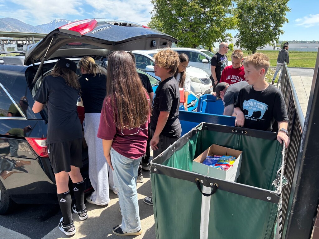 Students emptying supplies from a car into a cart.