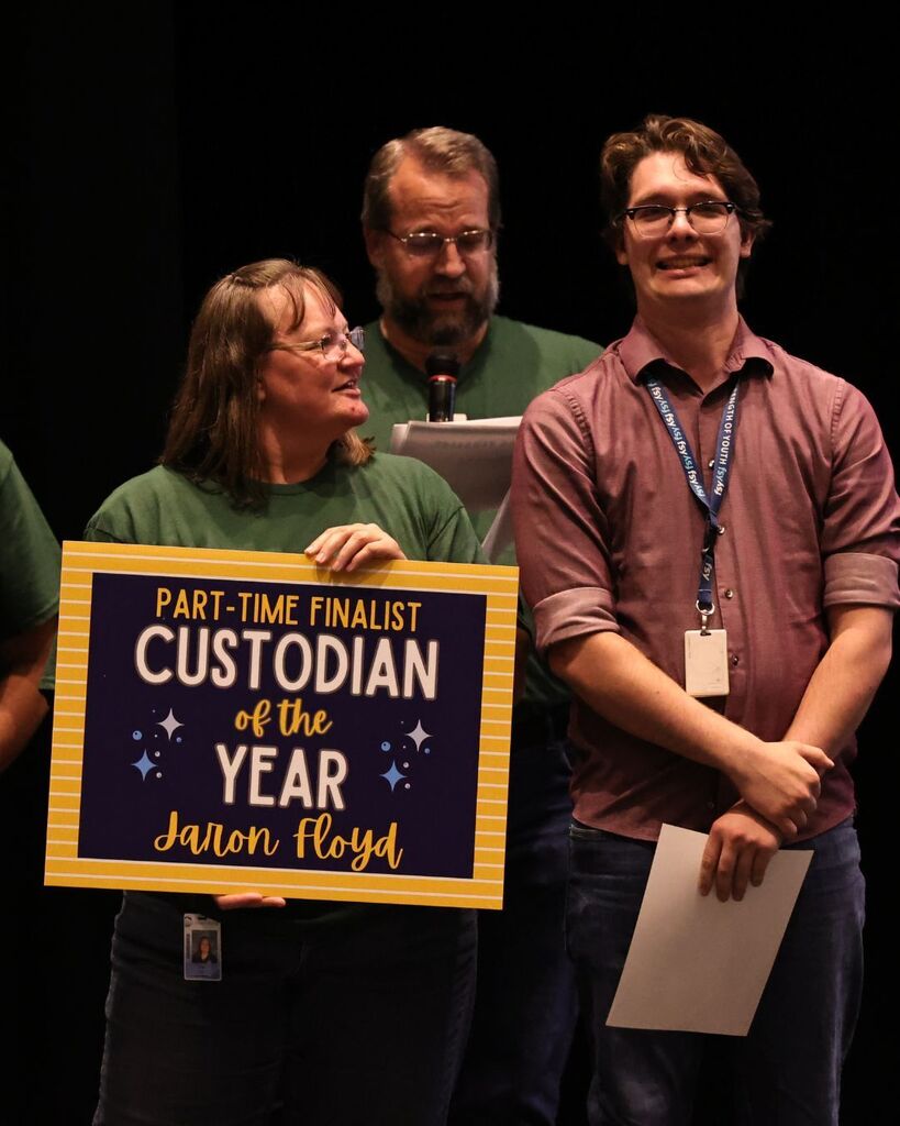 DSD custodians smiling. One is holding a sign that reads: "Part-Time Finalist Custodian of the Year Jaron Floyd."