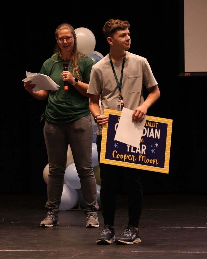 A student holds up a sign that says "cooper moon"
