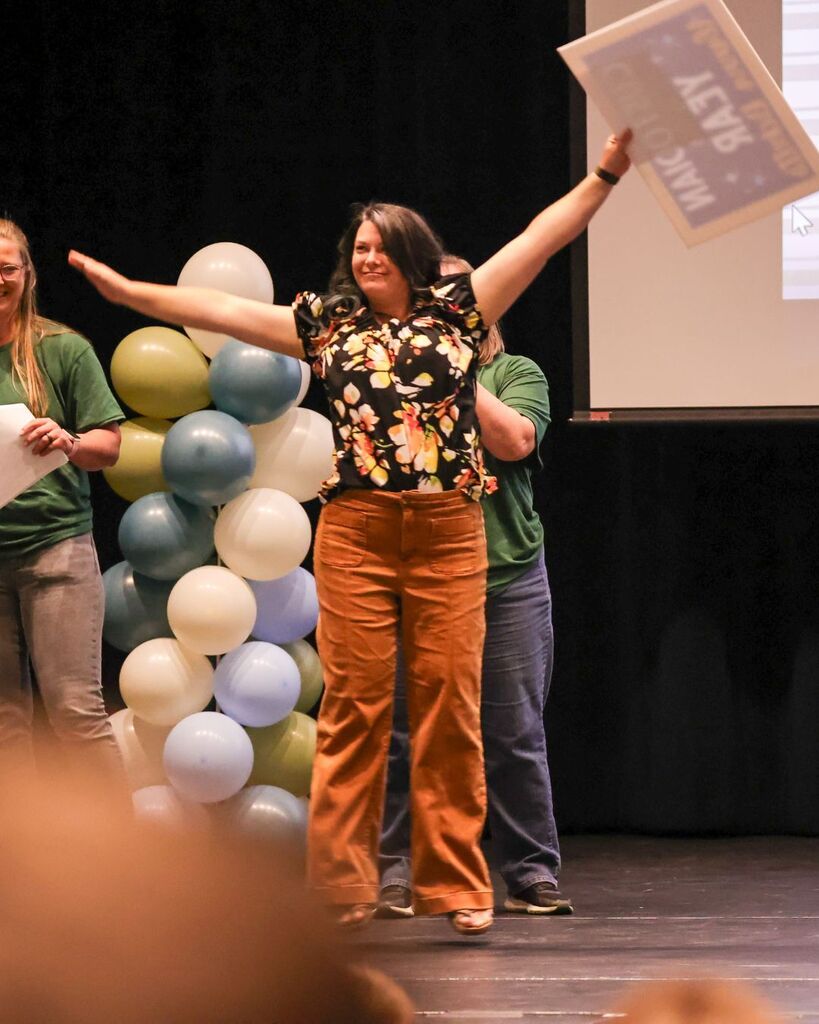 An employee raises up her hands in celebration.