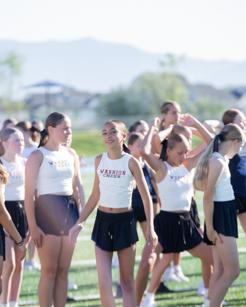 Cheerleaders practicing dance routine smiles at the camera