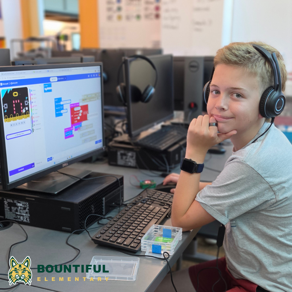 Bountiful elementary student wearing headphones while coding a micro:bit project on a computer.
