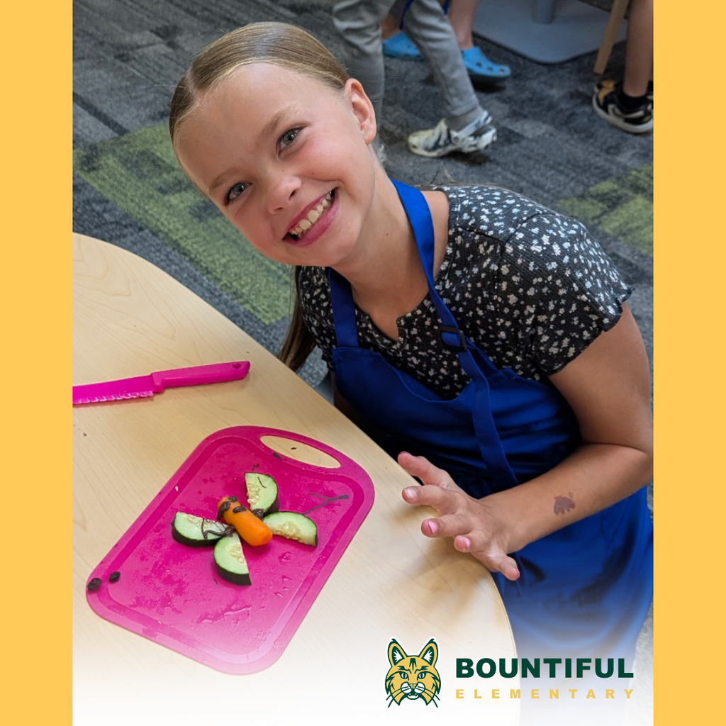 Bountiful elementary student smiles while making a fruit and vegetable butterfly snack.