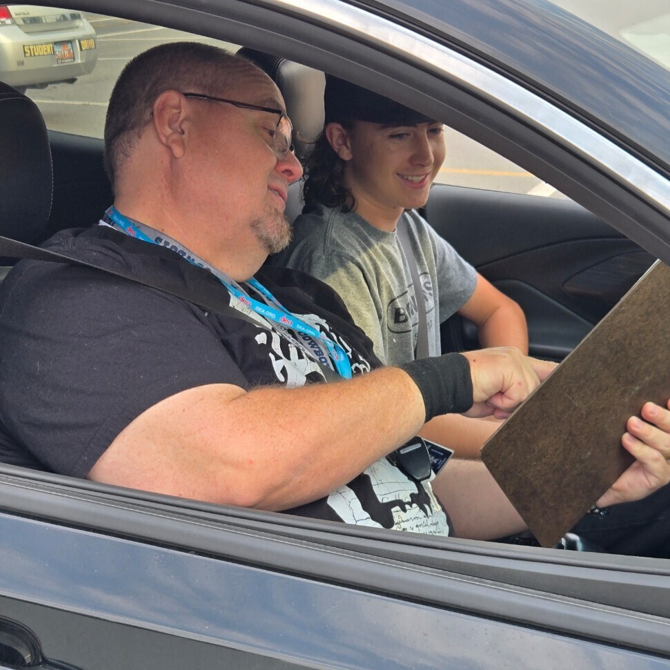 Mr. Shaffer provides some pro tips to a male student as they sit in a car