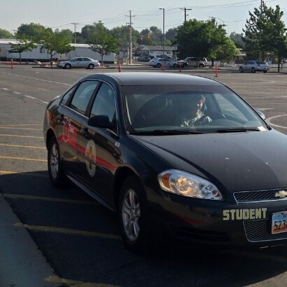 a male student smiles as he drives his car on the range