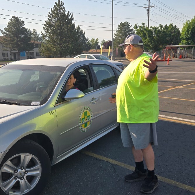 Mr. Shaffer standing outside a car on the range providing instruction to a student in the car
