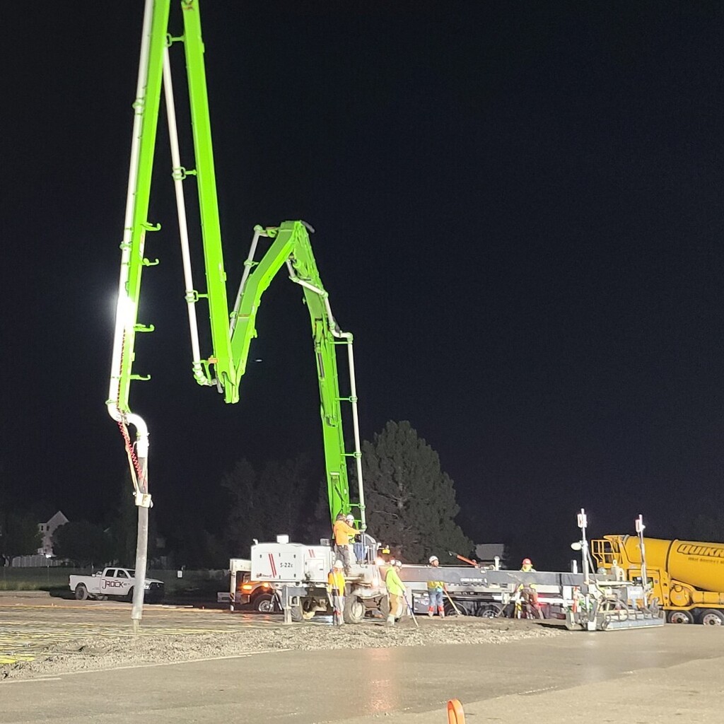 construction workers pumping new concrete gym floor before sunrise