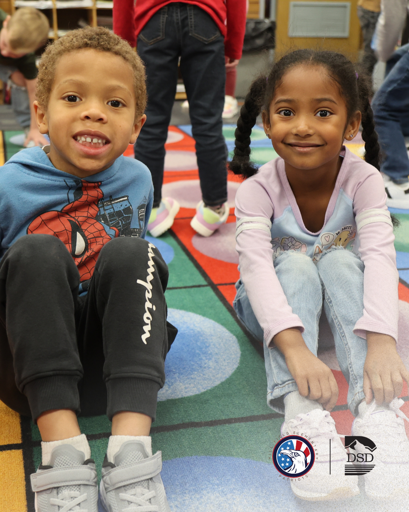 Two students smiling while showing us their shoes.