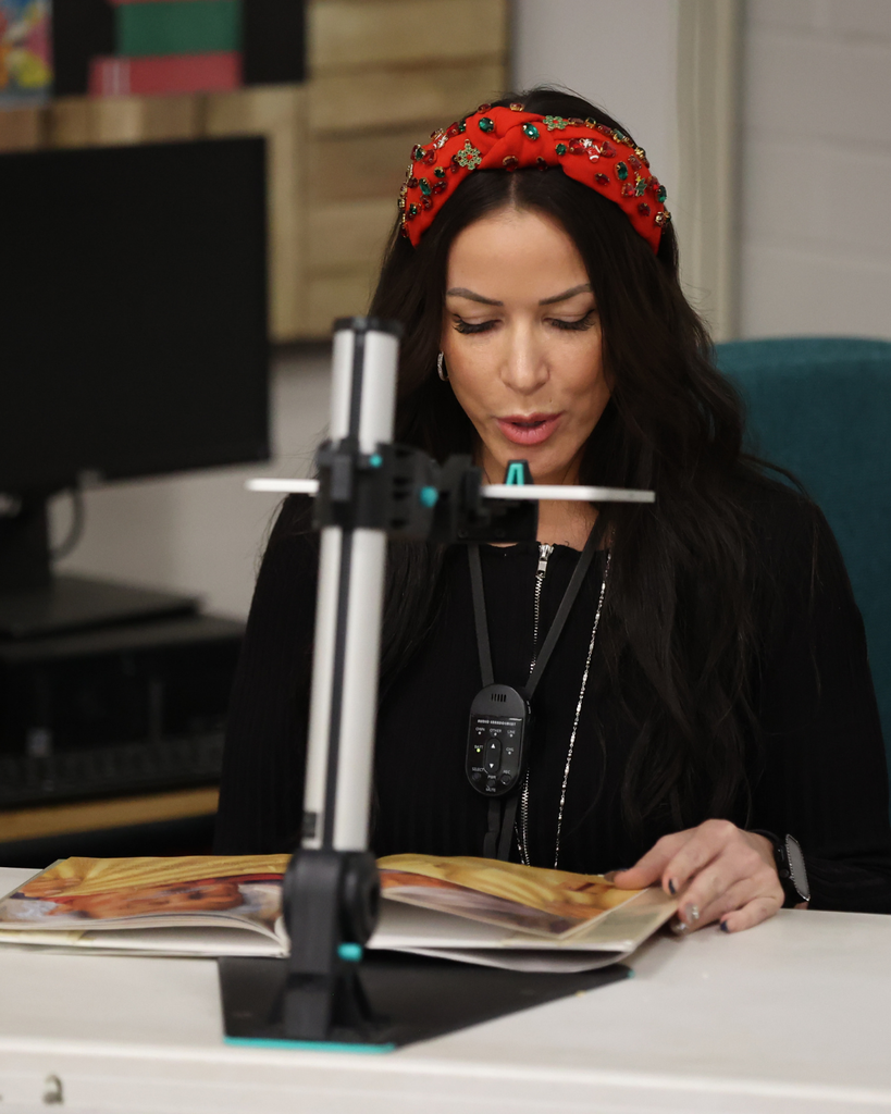 An adult reads a story while showing it from a projector.