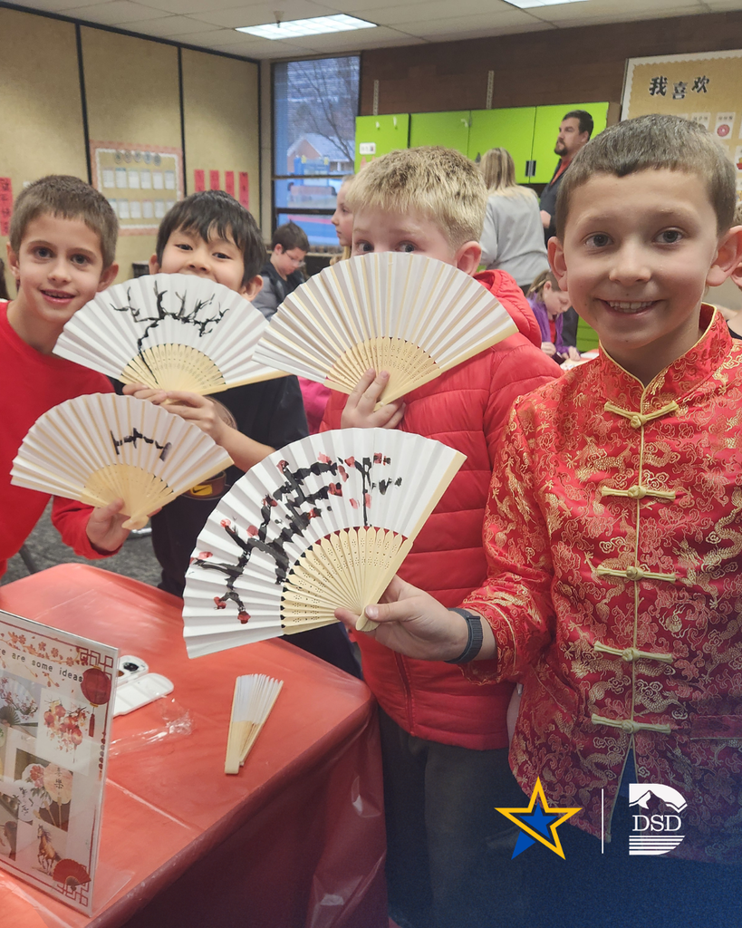 Students holding up fans that they painted.