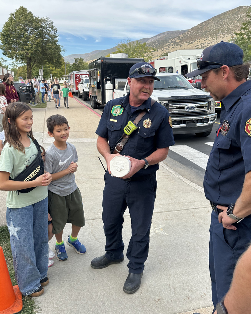 Students and fire fighters talking while a fireman holds a roll of towels.
