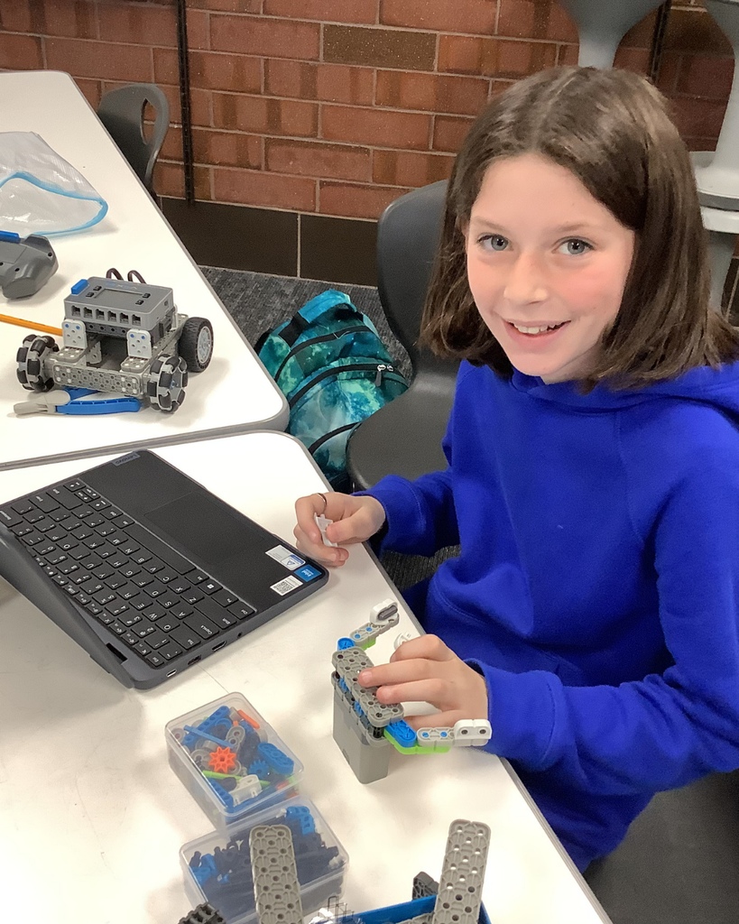 A student smiles as they work on their robot.