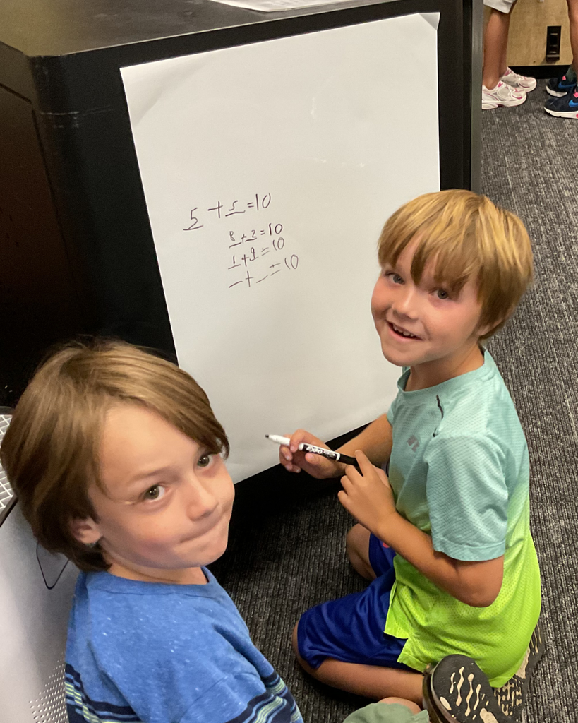 Two students smile as they solve a math problem.