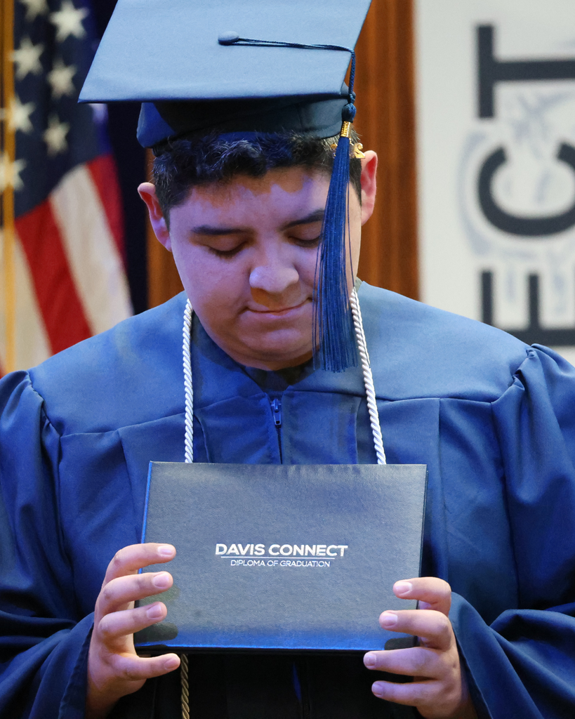 A Davis Connect graduate looks down at their diploma cover.