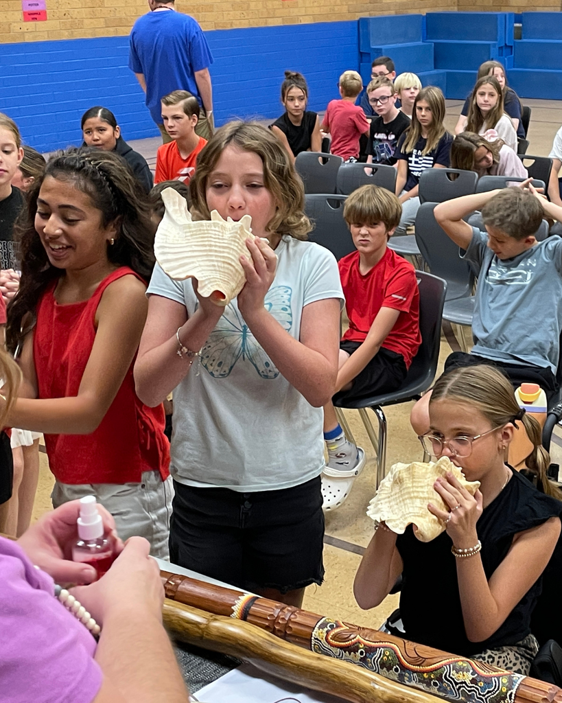 Students blowing into conch shells.