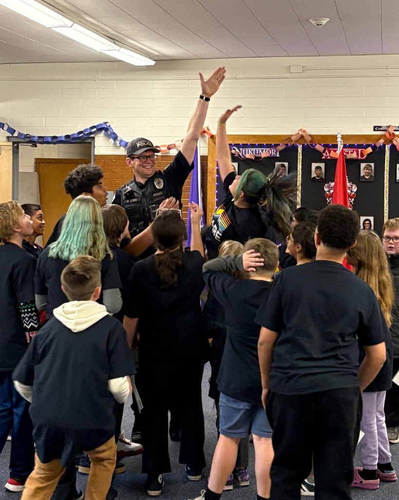 A group of students standing while one student is trying to high five a police officer.