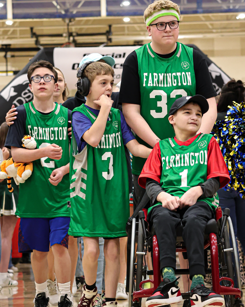 Students wearing green Farmington jerseys walk through a crowd.