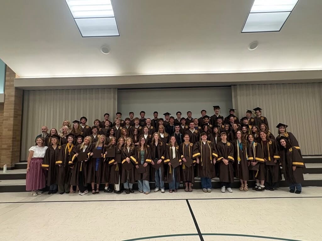 A large group of students in brown and gold graduation gowns.