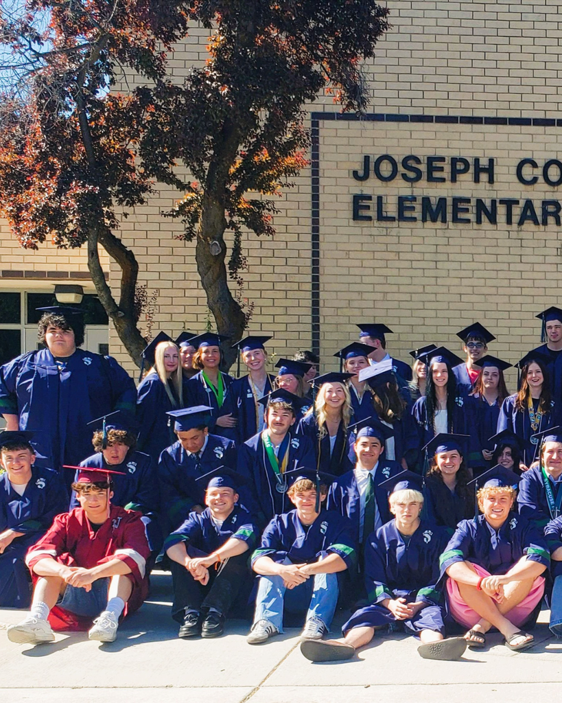 High school graduates posing in front of their elementary school.