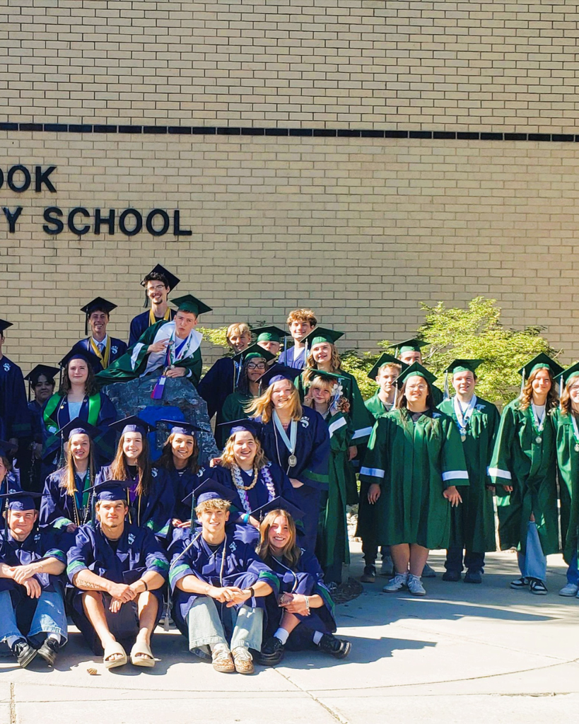 High school graduates posing in front of their elementary school.