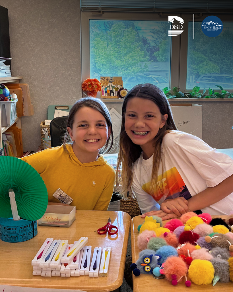 Students smiling while sitting at their desks.