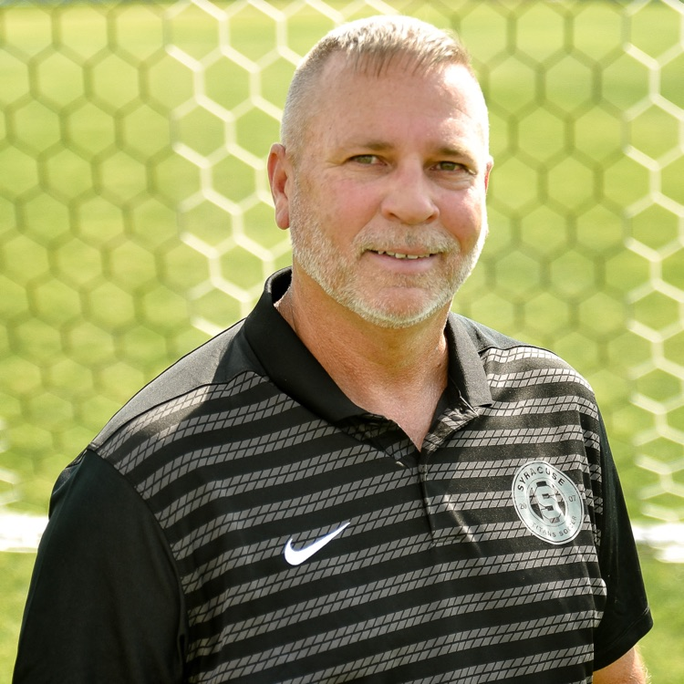 coach in black shirt on soccer field 
