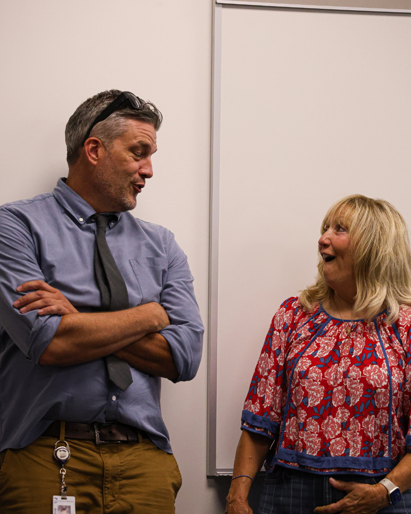 Two adults talking and looking surprised.