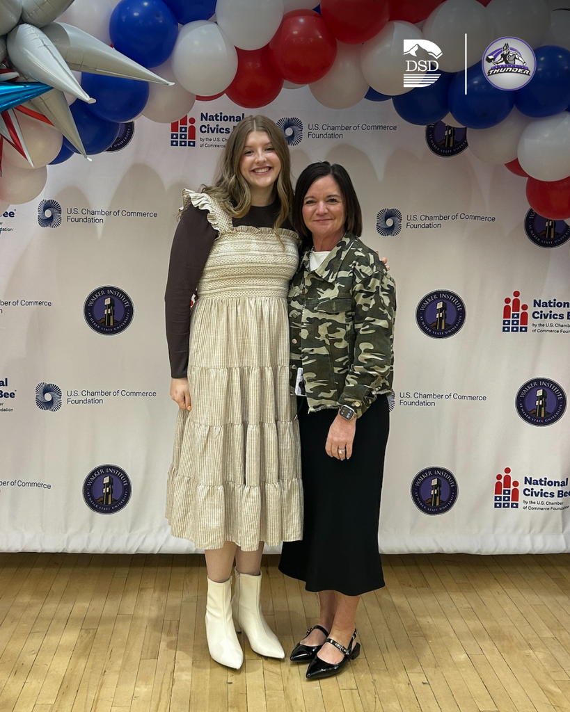 A student stands with her principal and poses. 