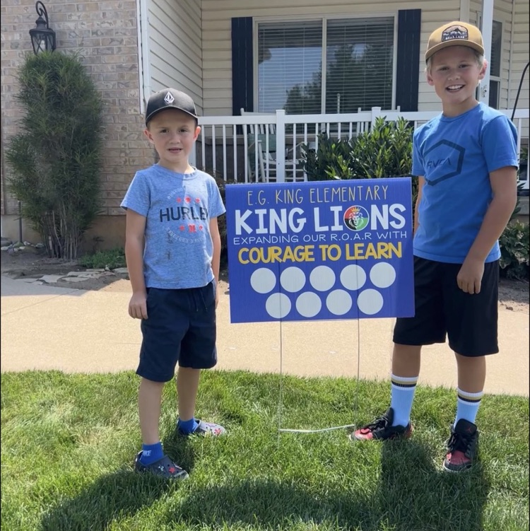 students posing with school yard sign 