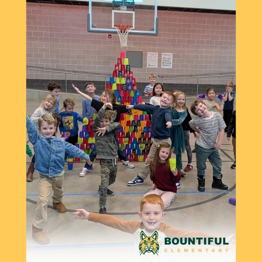 Bountiful Elementary students pose in the gym in front of a tall tower made from colorful stacking cups.