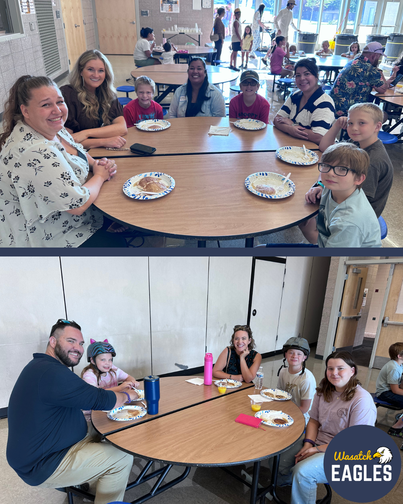 Families, students, and school staff gather in the school cafeteria during Pancakes with the Principals and PTA. Several groups sit together at round tables enjoying pancakes and visiting with one another. Plates of pancakes are visible on the tables, and families are engaged in conversation throughout the room.