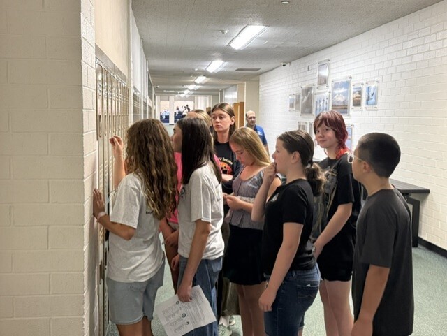 A group of incoming 7th grade students gathers in the school hallway, testing out their new lockers during Husky Camp.